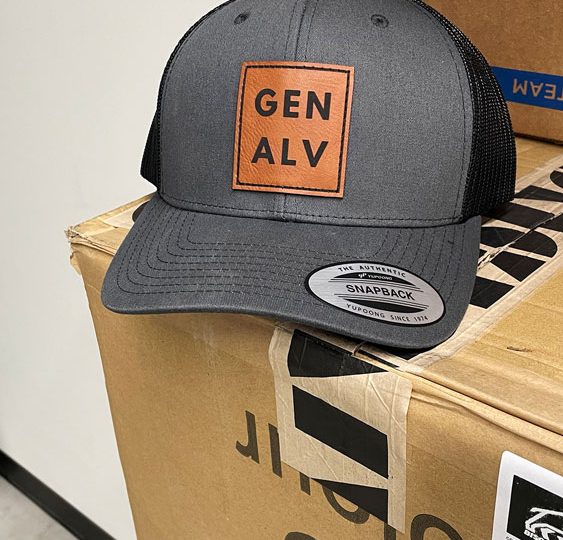 Gray trucker hat with a Gen Alv leather patch