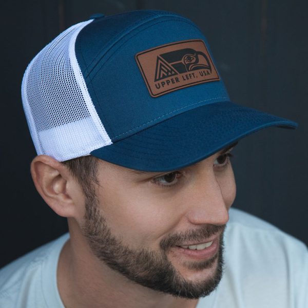 Man wearing a navy and white mesh trucker hat with an Upper Left USA leather patch